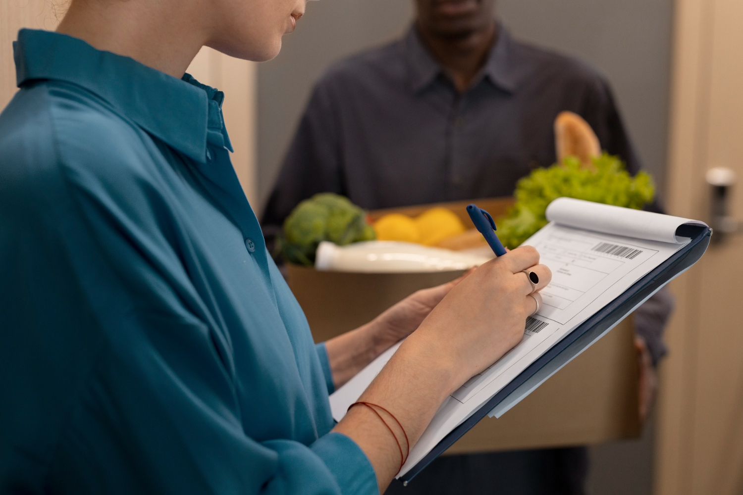 Inspectora de calidad revisando una entrega de alimentos con una lista de verificación en una tabla de apoyo.